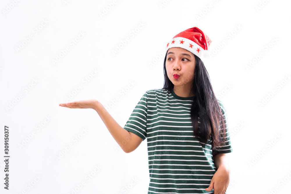 portrait of a young Asian woman wearing a santa hat and wearing casual clothes presents a copy space in the right hand portrait of a young Asian woman wearing a santa hat and wearing casual clothes presents a copy space in the right hand