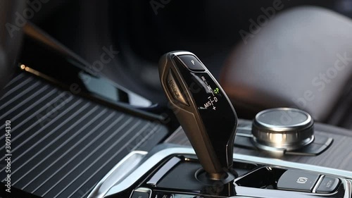 Close-up. Gear selector shift lever in the interior of a premium crossover. Handbrake buttons, brown leather interior. Touch panel to control functions.