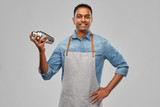 alcohol drinks, people and profession concept - indian barman in apron with cocktail shaker over grey background