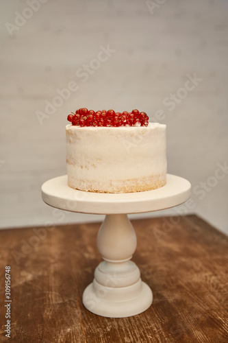 Sponge cake with cream decorated with redcurrant bunches on cake stand