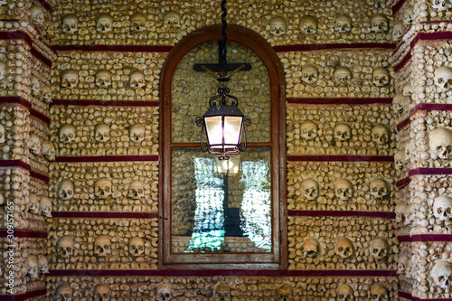 Fototapet Faro, Algarve / Portugal - Skulls and bones are embedded in the wall, a lantern