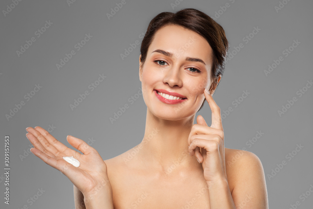 beauty, cosmetics and skincare concept - happy young woman with moisturizing cream on finger over grey background beauty, cosmetics and skincare concept - happy young woman with moisturizing cream on finger over grey background