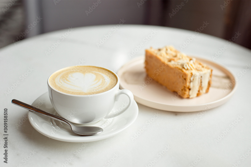Slice of caramel cake and a fork on the right side. A cup of hot coffee with ground in the background.Close-up. Slice of caramel cake and a fork on the right side. A cup of hot coffee with ground in the background.Close-up.