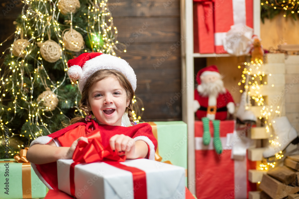 New year kids. Cheerful cute child opening a Christmas present. Christmas child holding a red gift box. Christmas Celebration holiday.