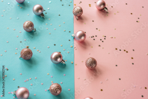 Christmas balls and confetti on a blue and pink background, New Year concept. Top view, close up.