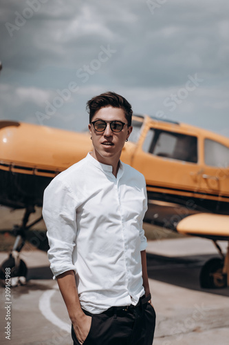 A man standing on the background of a small single engine plane. © teksomolika