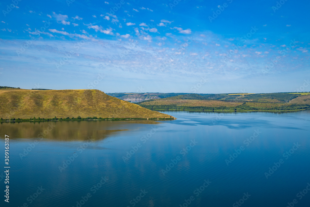 nature landscape wallpaper background scenic view photography in summer time peaceful lake water and green yellow hills horizon line clear blue sky