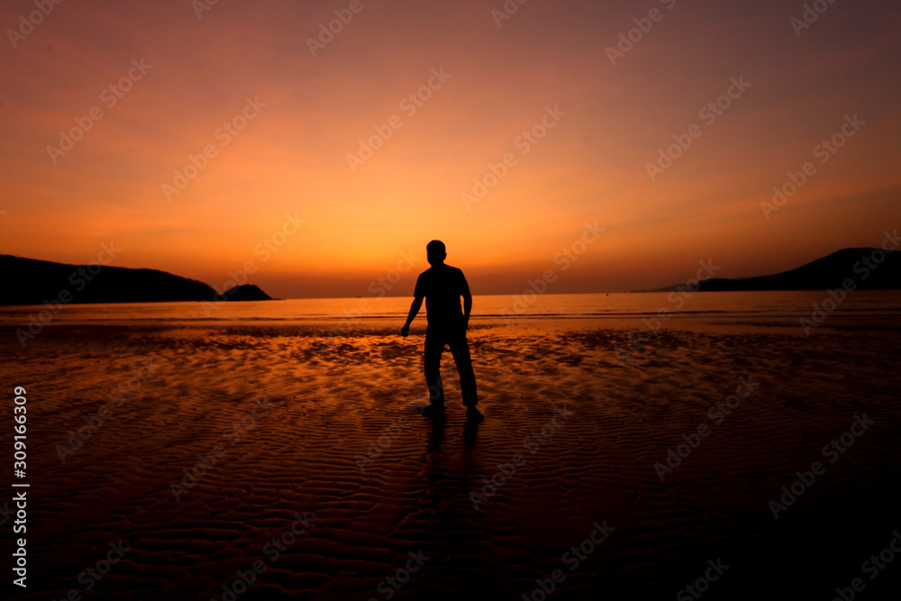 Silhouette action of a young man fun under twilight sunset sky at sea beach.