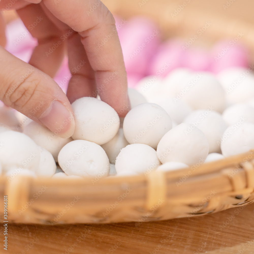 An Asia woman is making Tang yuan, yuan xiao, Chinese traditional food rice dumplings in red and white for lunar new year, winter festival, close up. An Asia woman is making Tang yuan, yuan xiao, Chinese traditional food rice dumplings in red and white for lunar new year, winter festival, close up.