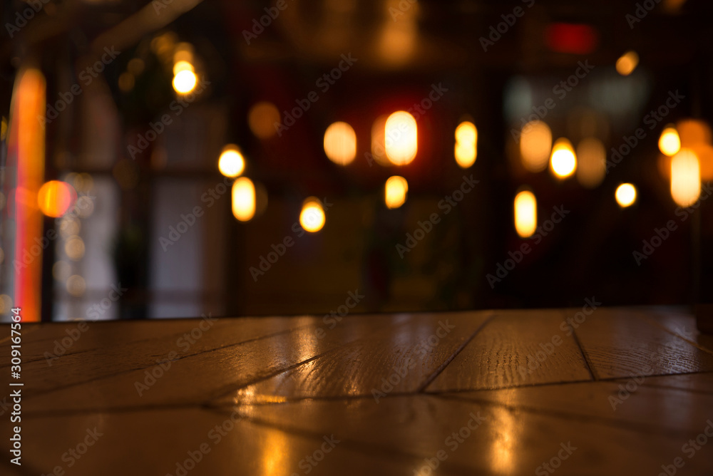 Image of wooden table in front of abstract blurred restaurant lights background