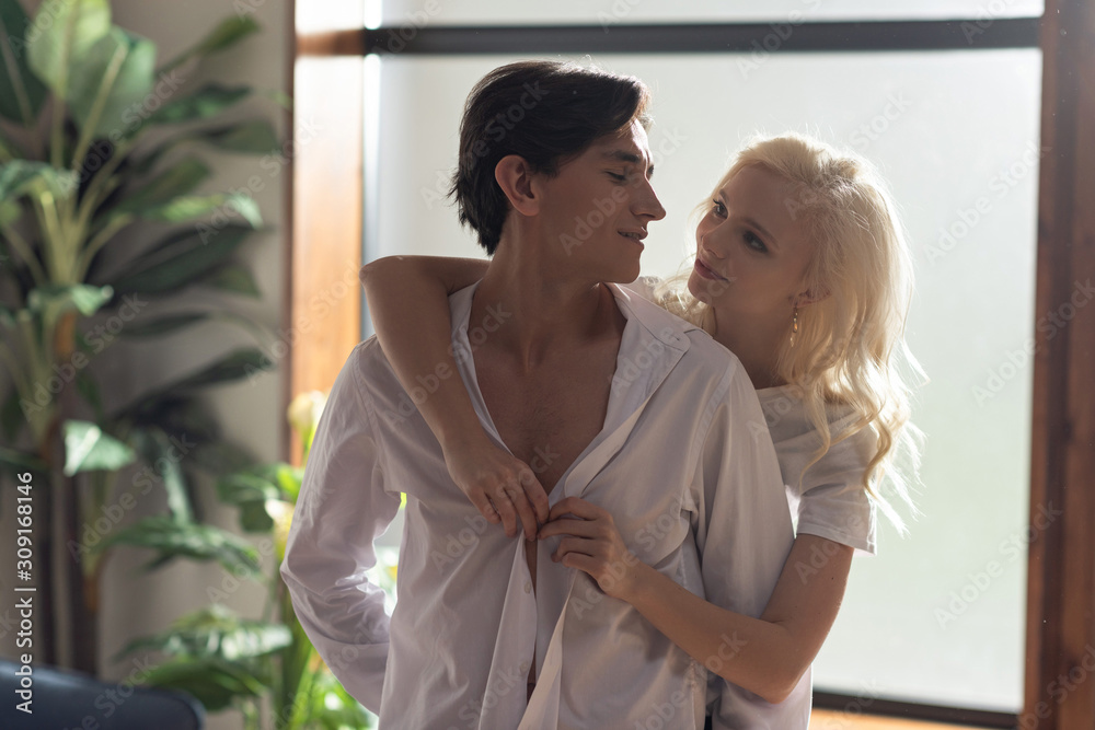 Young couple looking at each other while girl unbuttoning boyfriend shirt Young couple looking at each other while girl unbuttoning boyfriend shirt