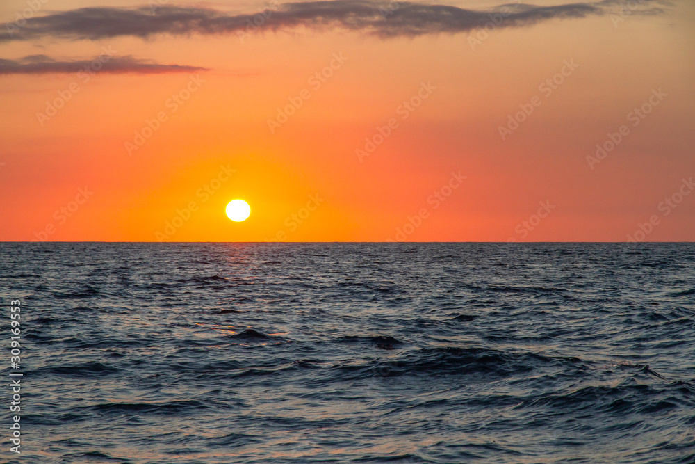 Beautiful sunset on the ocean. Orange sky and blue sea