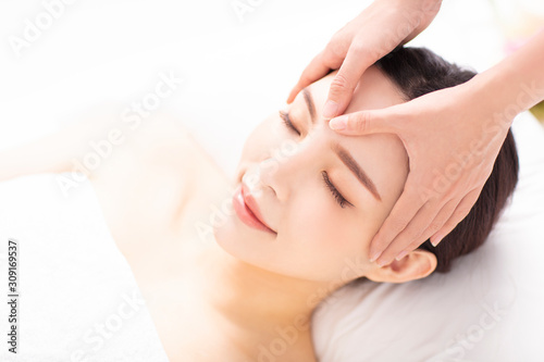 closed young woman face and head massage in spa photo