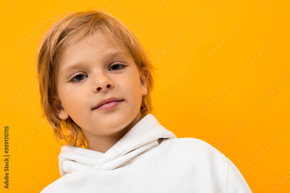 attractive blond boy in a white hoodie on an orange background attractive blond boy in a white hoodie on an orange background