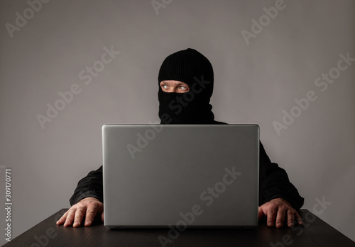 Hacker in mask using a laptop.