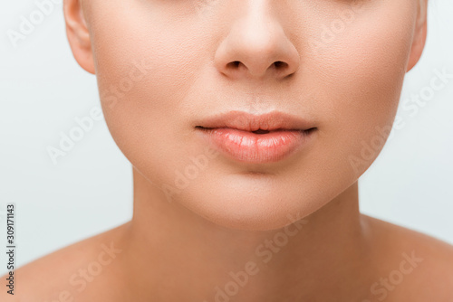 cropped view of young woman with lip gloss on lips isolated on white