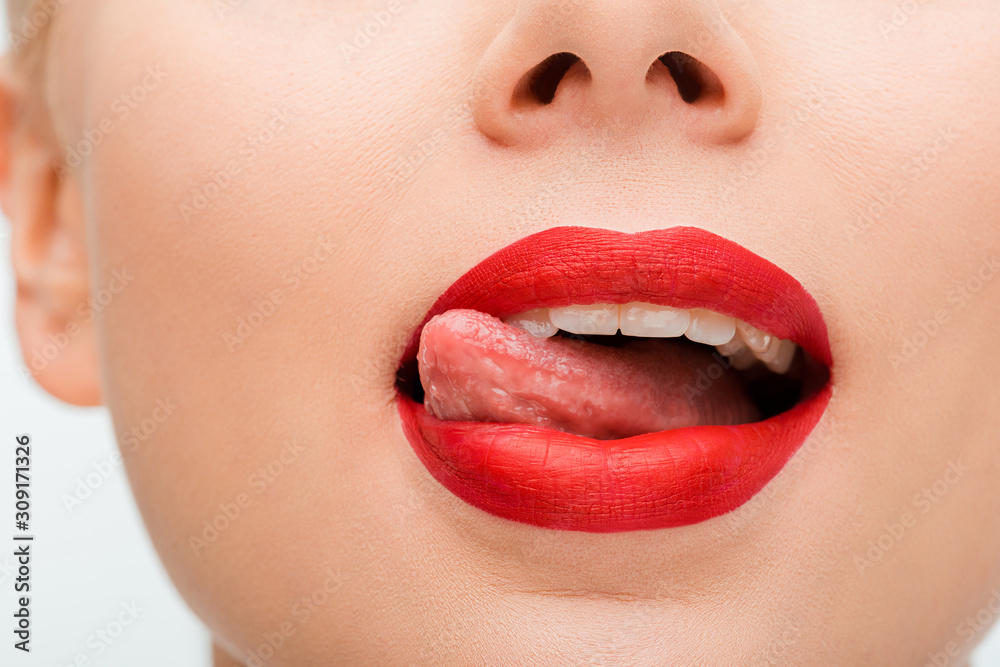 Obraz premium cropped view of woman with red lipstick licking lips isolated on white