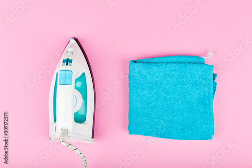 Iron on a pink background. View from above. iron with white and blue. With turquoise towel photo