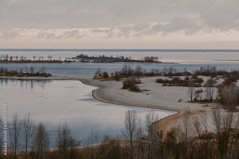 Panorama of wide river with sandy beach on winter day