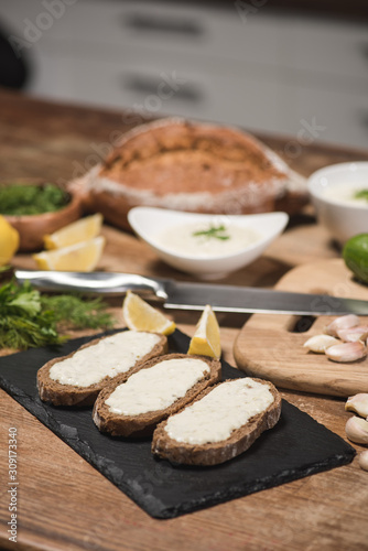 Bread with tzatziki sauce with fresh ingredients on wooden table