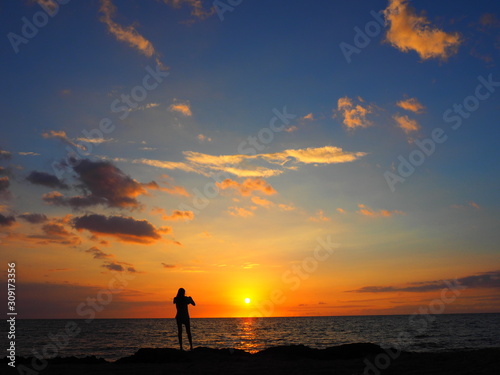 夕焼けの空と太陽と女性のシルエット