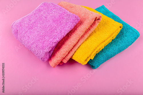 Multi-colored towels on a pink background. Pink, beige, yellow and blue flower towels. Place for writing. House order.