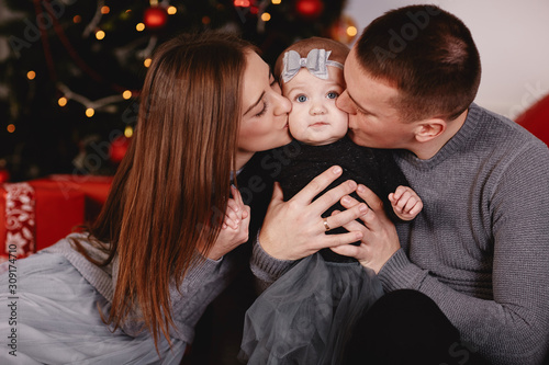 dad and mom kissing their little daughter. Beautiful young parents are kissing their cute little daughter, who is looking at camera and smiling