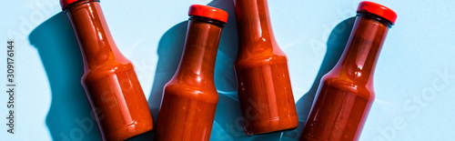 Fotografía Top view of bottles with tasty tomato sauce on blue background, panoramic shot