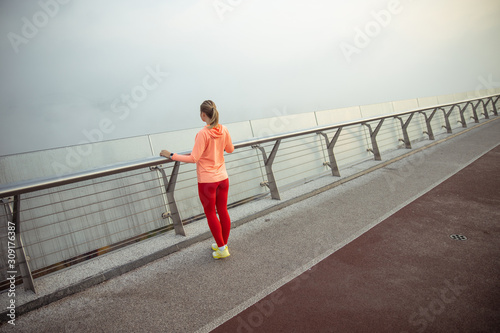 Fototapeta Naklejka Na Ścianę i Meble -  Sporty young woman standing on the bridge