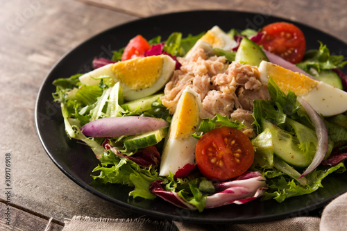Salad with tuna, egg and vegetables on wooden table 