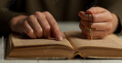 Foto Reading God's commandments in the Bible, close-up of a hand with a crucifix