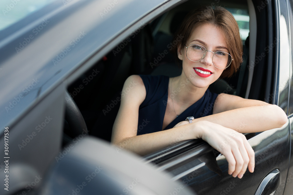 Beautiful girl in strict style of clothing gets out of the car for an important meeting in the office, goes for an interview