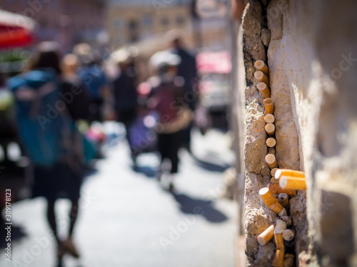 Cigarette ends stick to a gap in a wall on a market © Ewald Fröch