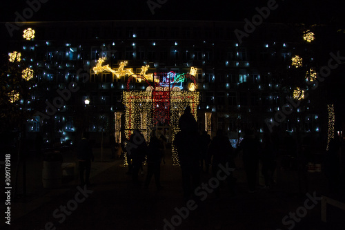 Colorful Christmas decorations and lights by night, New Year holiday decor, Varna city main square, people silhouettes