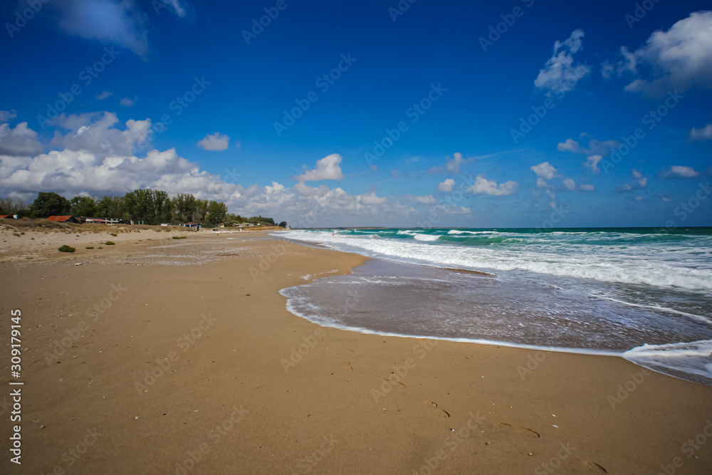 Obraz premium Empty sea beach. There are no steps in the sand. It's autumn. Only the waves leave a mark.