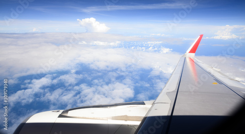 (Selective focus) Stunning view through the window of an airplane flying over some beautiful fluffy clouds.
