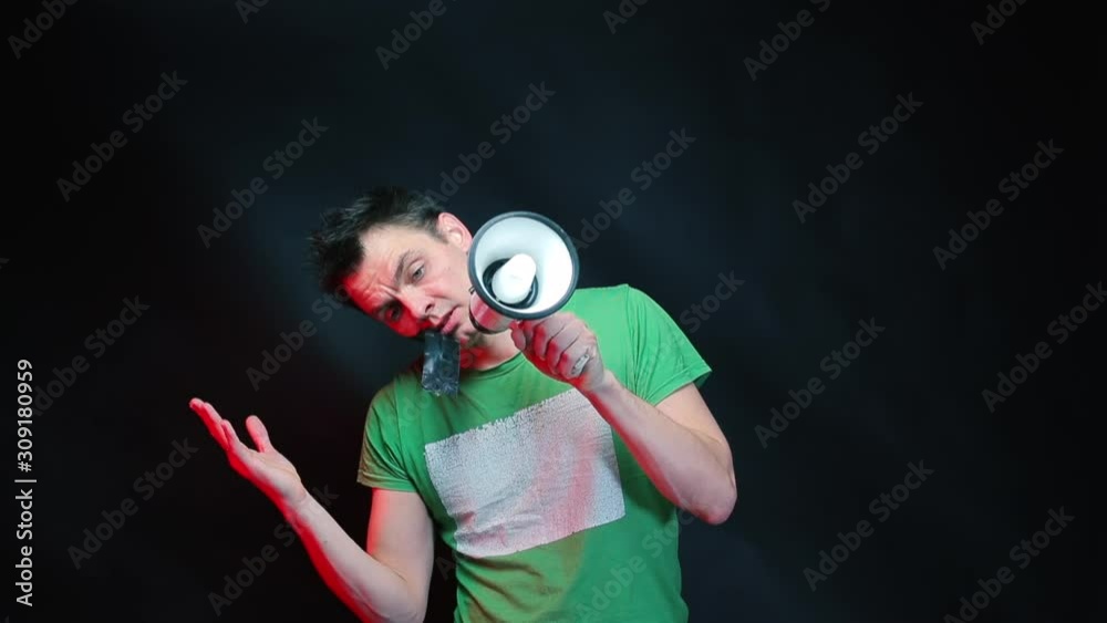A man in green clothes and a megaphone in his hands shouts. A man in green clothes and a megaphone in his hands shouts.