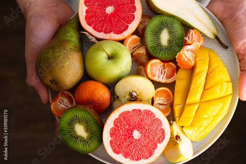 fresh fruits on a plate in male hands