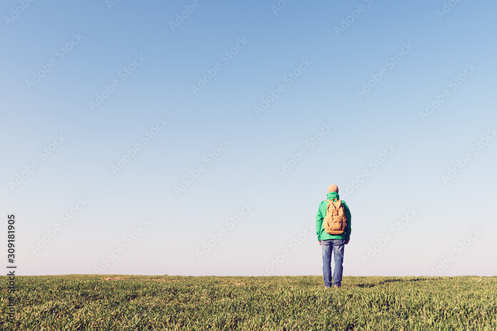 Tourist with backpack alone on summer field. Travel concept