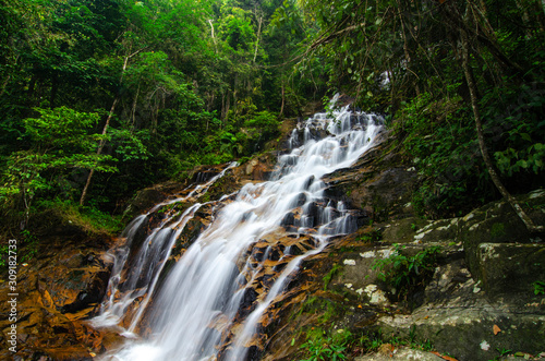 Beautiful tropical waterfall in lush surrounded by green forest.wet rock and moss.selective focus shot.