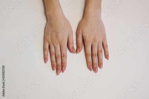 beautiful female hands with beige manicure on a white background