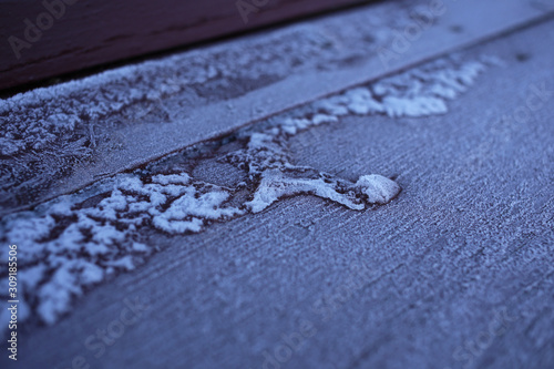 Frozen moisture on the surface of a wooden bench. © Ihor95