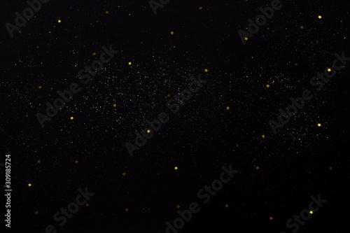 Golden stars and sparkles on black background. Starry sky.