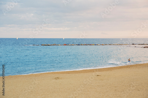 View of Barcelona beach, in the Barceloneta district, overlooking the Mediterranean Sea. The sky is dark and there are many waves.