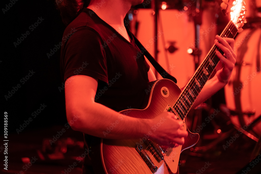 Obraz premium Man playing guitar on the stage at the concert