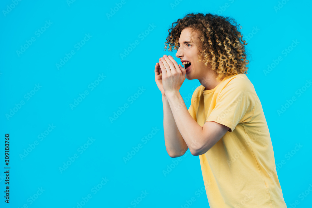 angry curly teenager yelling isolated on blue angry curly teenager yelling isolated on blue