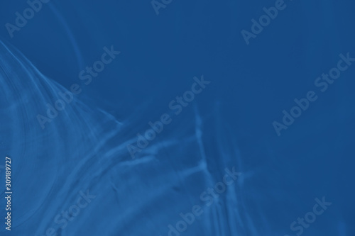 Trendy blue colored low contrast abstract background with light and shadows caustic effect. Light passes through a glass. Water background. 2020 year color trend © Aleksandra Konoplya