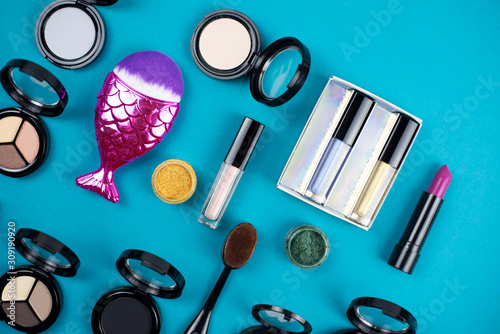 Flat lay a variety of cosmetics and accessories on a turquoise background.