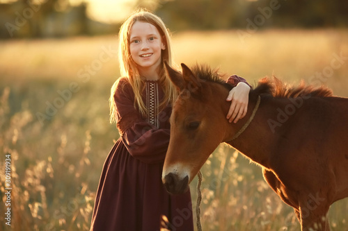 A farmer girl walks a horse in a yellow meadow.