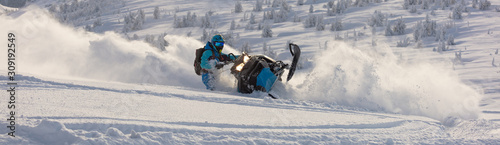 Pro snowmobiler makes a turn and lets a flurry of snow spray from under the caterpillar. sports snowmobile in the mountains. bright skidoo motorbike and suit without brands. Winter fun moto extreme